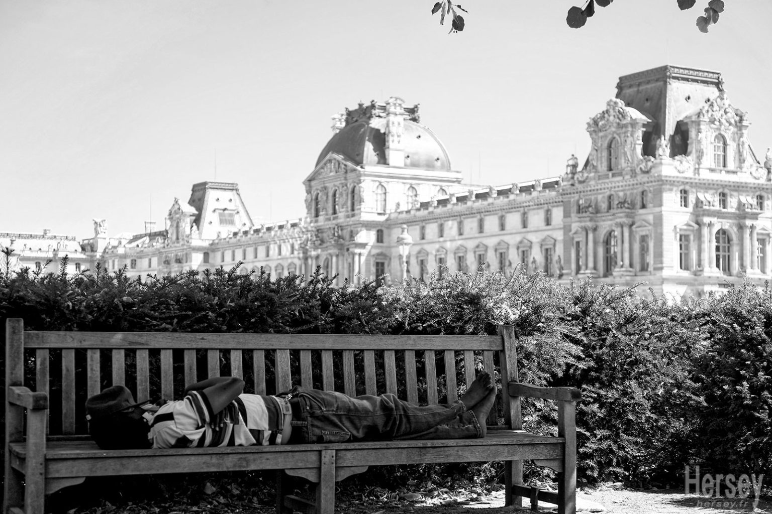 SDF couché sur un banc devant le palais du Louvre Paris