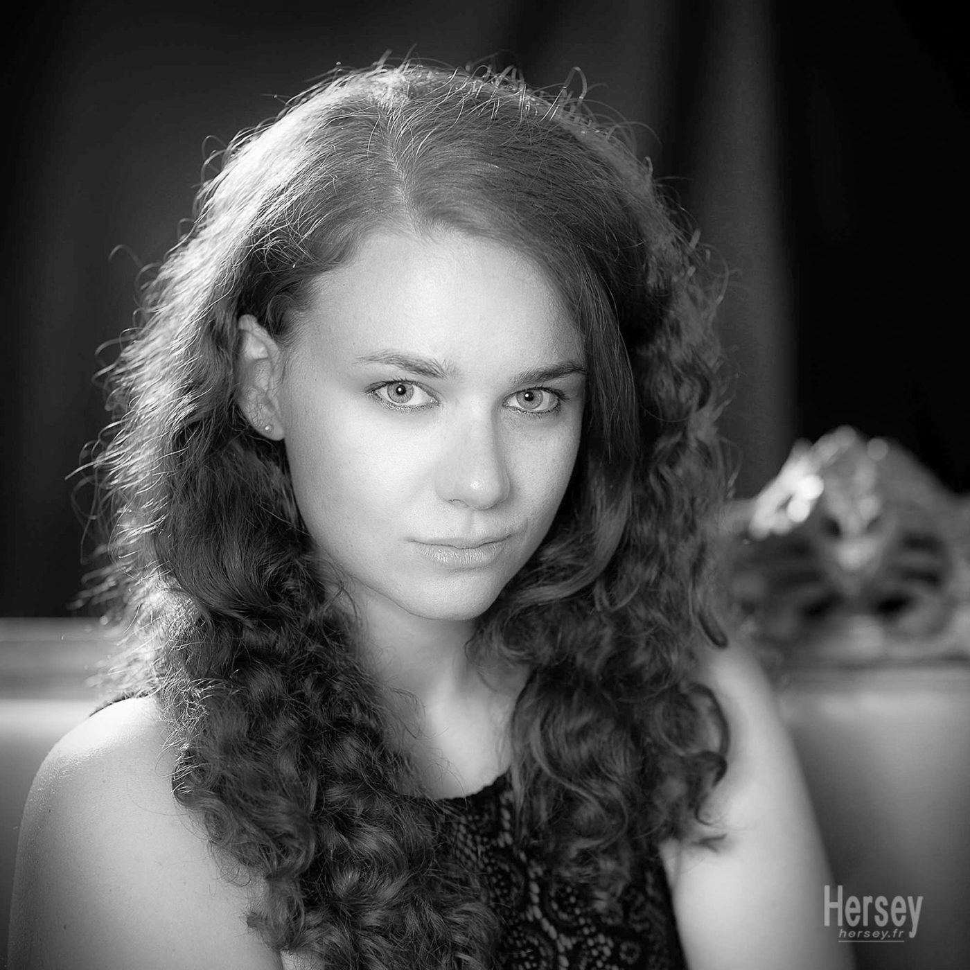 Portrait de Naïs en noir et blanc. Jeune femme aux cheveux ondulés et aux yeux clairs © Hersey Photographe portrait Nîmes Gard